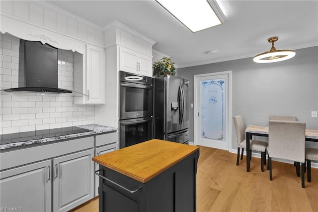 kitchen with tasteful backsplash, stainless steel appliances, wall chimney range hood, light hardwood / wood-style floors, and white cabinetry