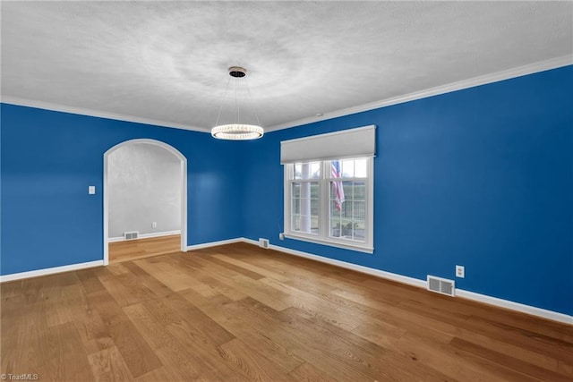 spare room with hardwood / wood-style floors, an inviting chandelier, and ornamental molding