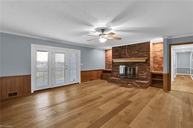 unfurnished living room featuring light hardwood / wood-style floors, a brick fireplace, ceiling fan, and ornamental molding