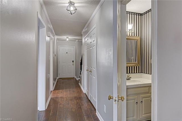 corridor with sink, crown molding, dark hardwood / wood-style flooring, and a textured ceiling