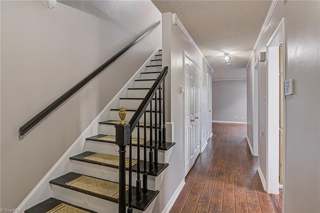 stairs featuring wood-type flooring, a textured ceiling, and ornamental molding