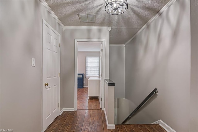 corridor with a textured ceiling, crown molding, and dark hardwood / wood-style floors