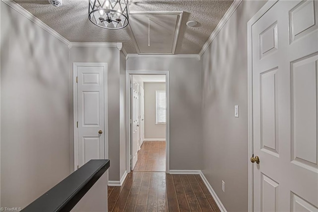 hallway featuring a textured ceiling, crown molding, dark wood-type flooring, and an inviting chandelier