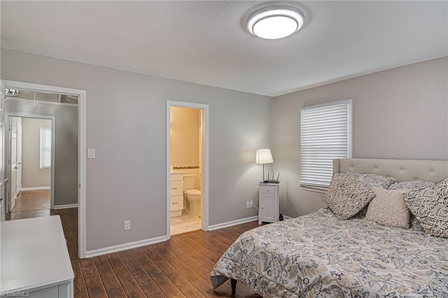 bedroom with connected bathroom, dark hardwood / wood-style flooring, and multiple windows