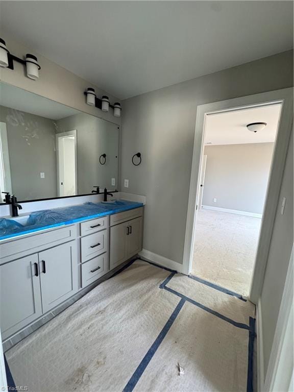 full bathroom featuring a sink, baseboards, and double vanity