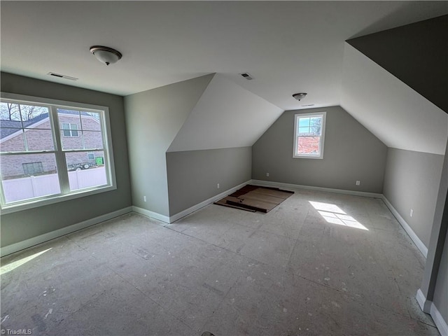 additional living space featuring visible vents, vaulted ceiling, and baseboards