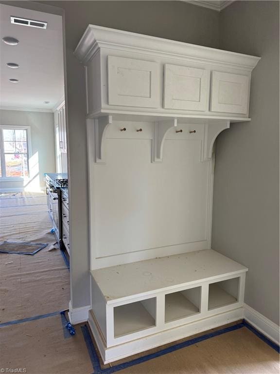 mudroom with baseboards, visible vents, dark wood finished floors, and ornamental molding