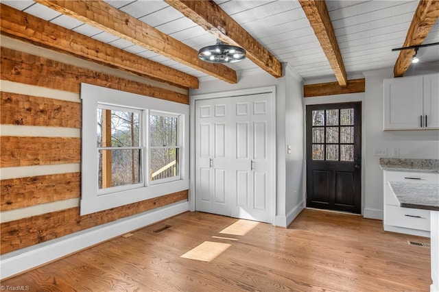 interior space featuring light wood-type flooring, wood ceiling, baseboards, and beam ceiling