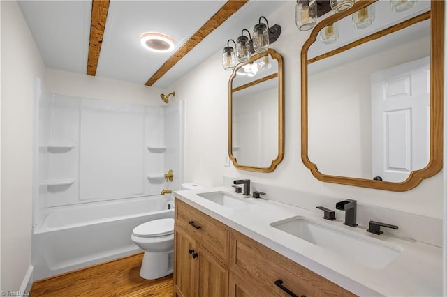 full bathroom featuring toilet, double vanity, a sink, and wood finished floors