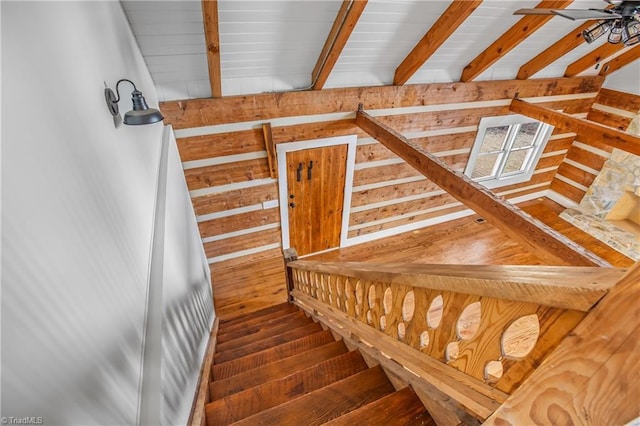 stairway featuring ceiling fan, hardwood / wood-style floors, wood walls, and beam ceiling