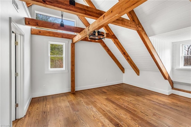 additional living space featuring lofted ceiling with beams, wood finished floors, and a healthy amount of sunlight