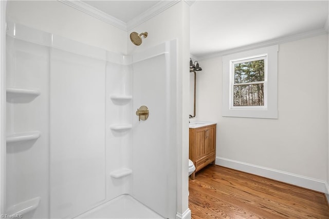 bathroom with wood finished floors, vanity, baseboards, walk in shower, and crown molding