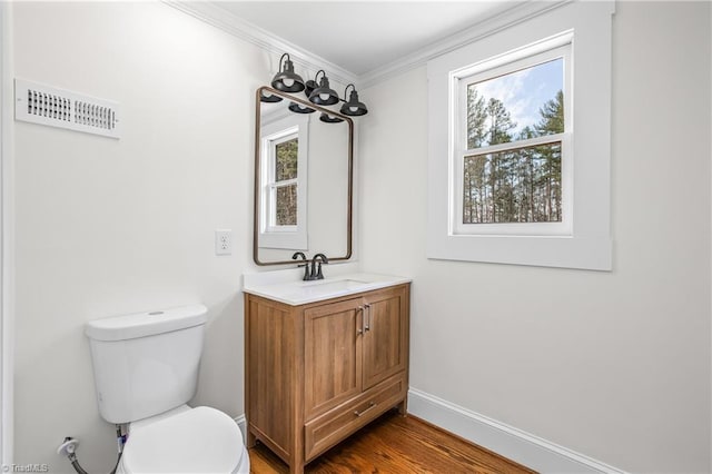 bathroom featuring visible vents, toilet, ornamental molding, wood finished floors, and baseboards