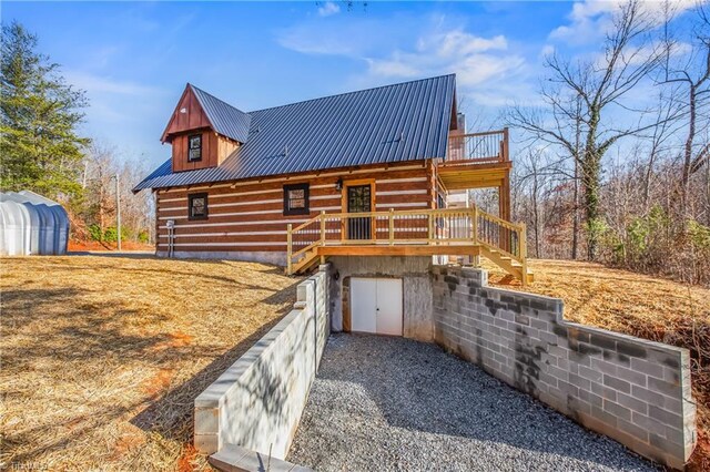 view of side of property with stairs, metal roof, log exterior, and a wooden deck