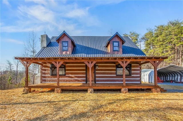 view of front of home featuring a carport, covered porch, metal roof, and a chimney