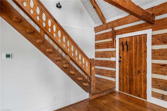 staircase featuring lofted ceiling with beams, wooden ceiling, and wood finished floors