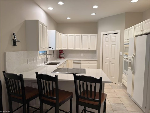 606 Dorado Cir, High Point, NC 27265 - kitchen with a sink, white appliances, a peninsula, a kitchen bar, and recessed lighting