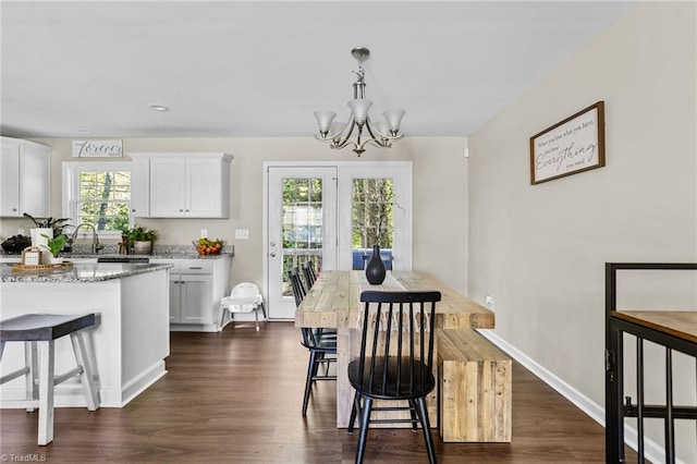 dining area with sink, dark hardwood / wood-style flooring, and an inviting chandelier