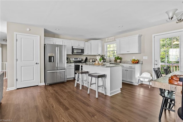 kitchen featuring a center island, white cabinetry, stainless steel appliances, and a healthy amount of sunlight