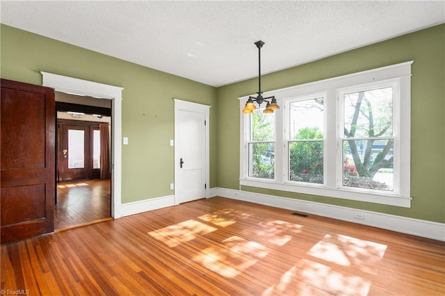 104 E Wilson St, Mebane, NC 27302 - unfurnished dining area featuring wood finished floors, plenty of natural light, baseboards, and a textured ceiling