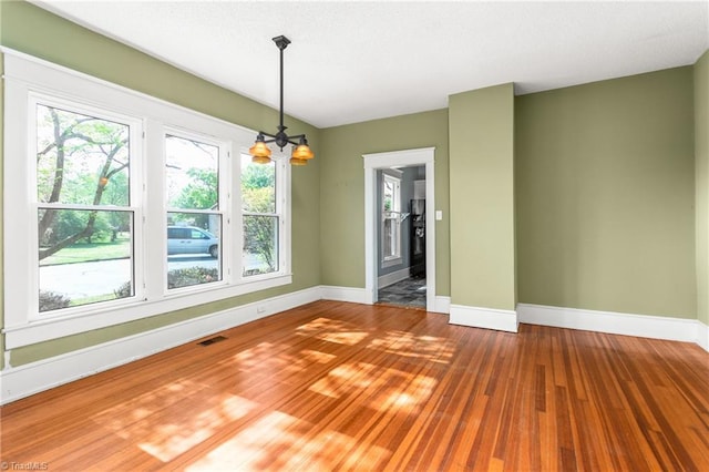 104 E Wilson St, Mebane, NC 27302 - unfurnished dining area featuring baseboards, wood finished floors, and a chandelier