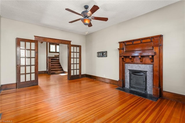 104 E Wilson St, Mebane, NC 27302 - unfurnished living room with french doors, wood finished floors, ceiling fan, a tiled fireplace, and baseboards