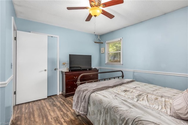 bedroom with a textured ceiling, a closet, wood finished floors, and a ceiling fan