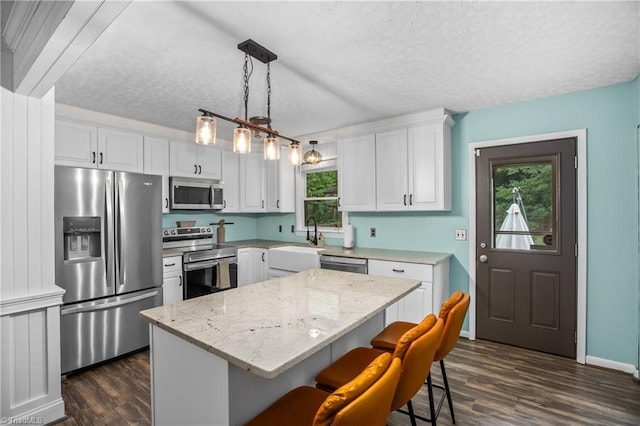 kitchen featuring a textured ceiling, stainless steel appliances, a sink, and dark wood finished floors