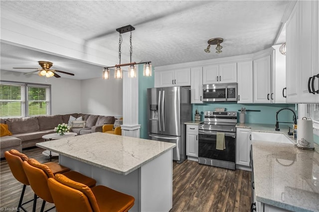 kitchen featuring open floor plan, dark wood-style flooring, stainless steel appliances, a textured ceiling, and a sink