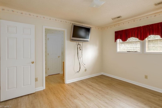 unfurnished room with hardwood / wood-style flooring and a textured ceiling