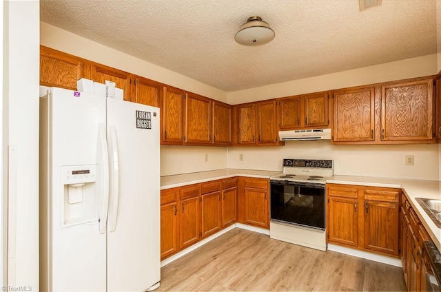 kitchen with electric stove, white refrigerator with ice dispenser, a textured ceiling, and light wood-type flooring