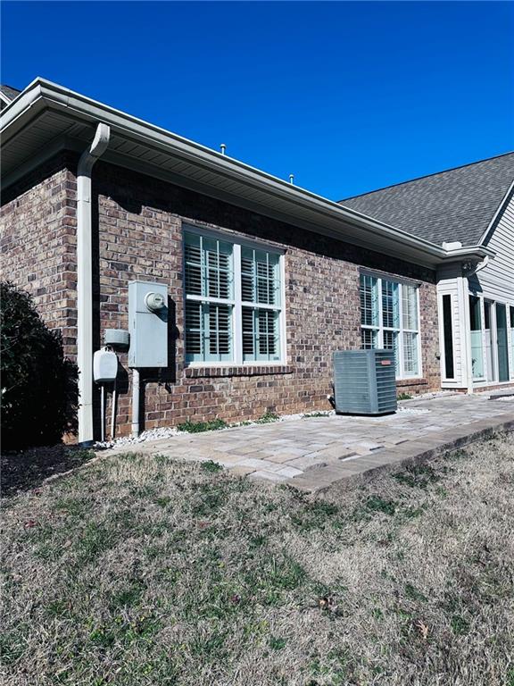 view of side of property featuring cooling unit, a patio area, and a lawn