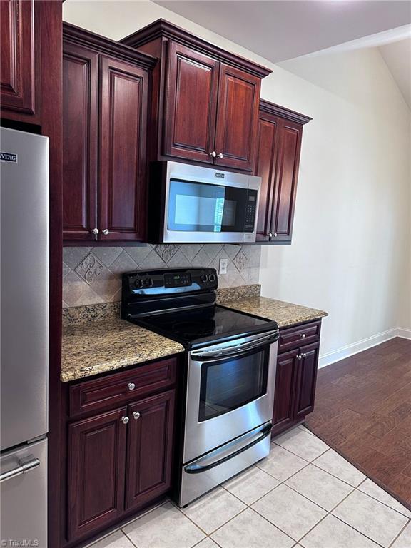 kitchen with light stone counters, light tile patterned floors, decorative backsplash, and appliances with stainless steel finishes