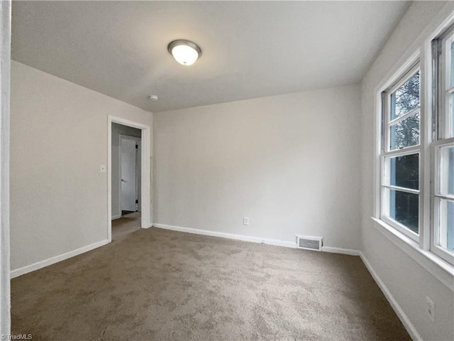 unfurnished room with dark carpet and a healthy amount of sunlight