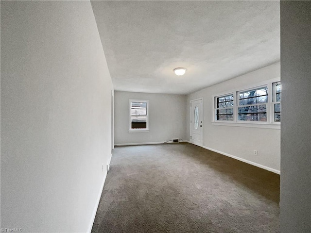 spare room with dark colored carpet and a textured ceiling