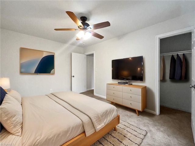 bedroom featuring a walk in closet, a closet, light colored carpet, and ceiling fan