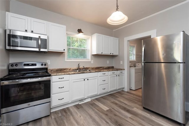 712 Englewood St, Greensboro, NC 27403 - kitchen featuring appliances with stainless steel finishes, washing machine and clothes dryer, a sink, white cabinets, and healthy amount of natural light