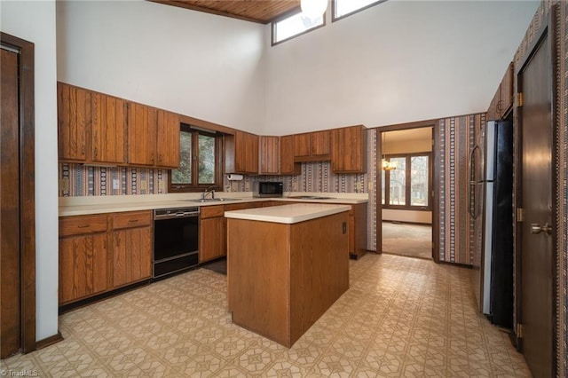 kitchen featuring black dishwasher, light floors, light countertops, brown cabinetry, and a kitchen island