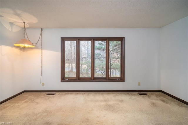 carpeted empty room featuring visible vents, a textured ceiling, and baseboards