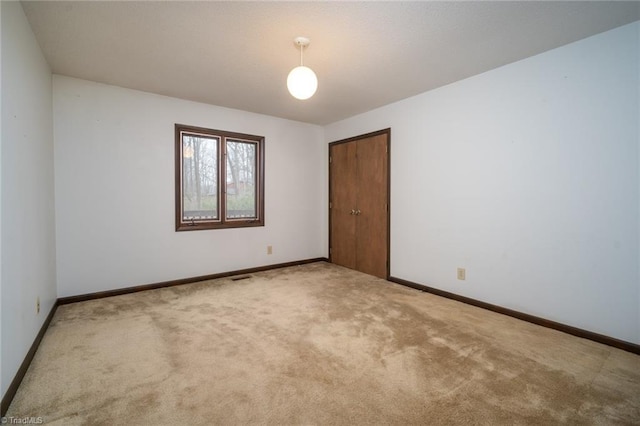 carpeted spare room featuring baseboards