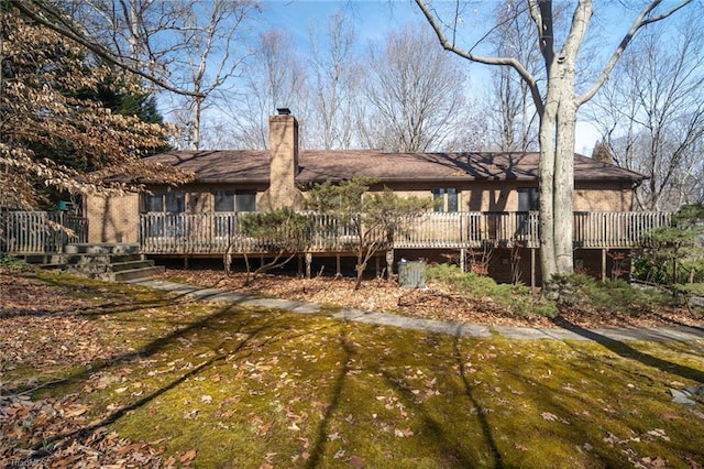 rear view of property featuring a lawn, a chimney, and a wooden deck