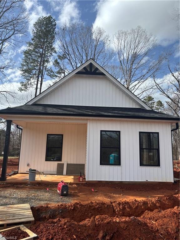 view of side of property featuring a porch and roof with shingles