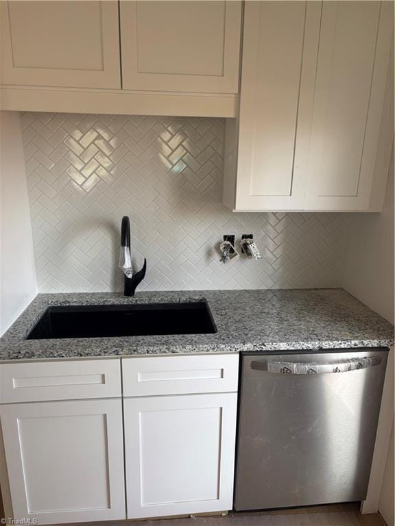 kitchen with backsplash, white cabinetry, a sink, light stone countertops, and dishwasher