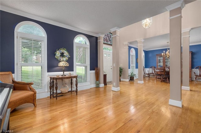 6516 Dornoch Dr, Greensboro, NC 27410 - foyer entrance with ornate columns, a chandelier, crown molding, wood finished floors, and a textured ceiling