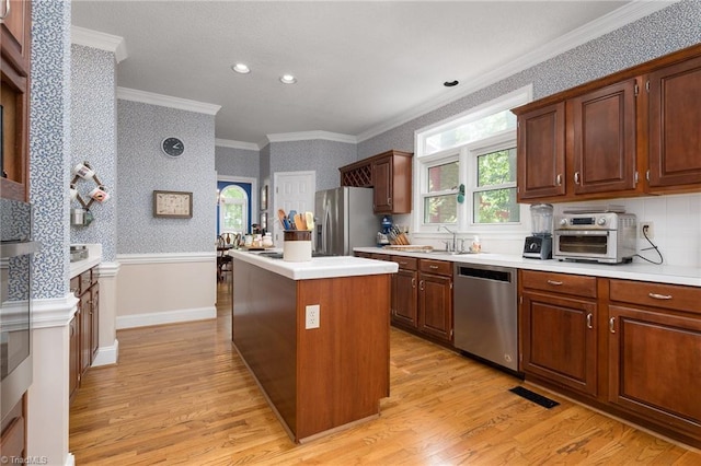 6516 Dornoch Dr, Greensboro, NC 27410 - kitchen featuring appliances with stainless steel finishes, a center island, ornamental molding, light wood-style flooring, and wallpapered walls