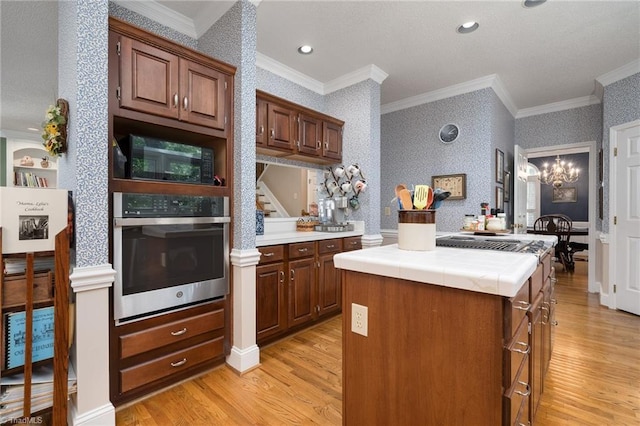 6516 Dornoch Dr, Greensboro, NC 27410 - kitchen featuring stainless steel appliances, tile counters, light wood-style floors, crown molding, and wallpapered walls