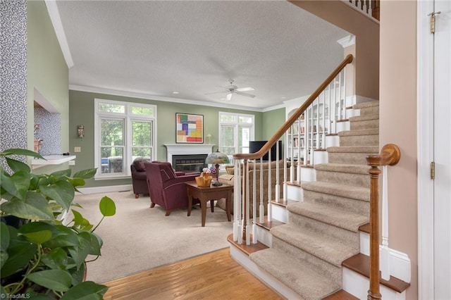 6516 Dornoch Dr, Greensboro, NC 27410 - living area featuring crown molding, stairs, ceiling fan, a textured ceiling, and a glass covered fireplace