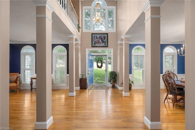 6516 Dornoch Dr, Greensboro, NC 27410 - foyer featuring decorative columns, light wood finished floors, baseboards, a textured ceiling, and ornamental molding