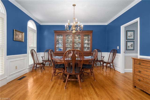 6516 Dornoch Dr, Greensboro, NC 27410 - dining room with a chandelier, light wood-style flooring, a wainscoted wall, and crown molding