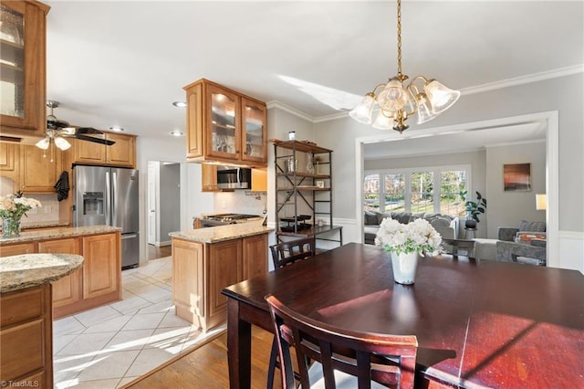 dining area with ornamental molding, ceiling fan with notable chandelier, and light tile patterned flooring